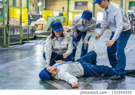 一群人為一名在工廠暈倒的工人提供醫療救助 131954595