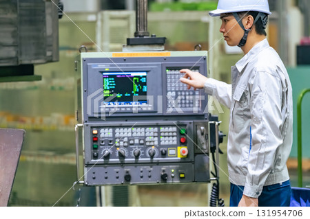 A worker operating a machine on a factory control panel 131954706