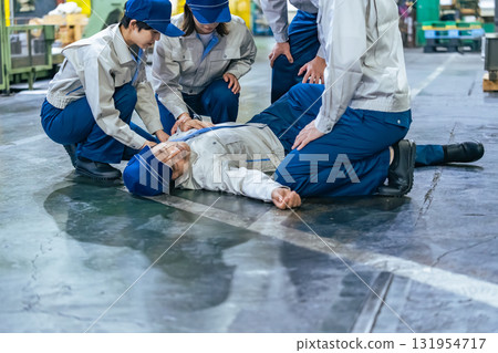 一群人為一名在工廠暈倒的工人提供醫療救助 131954717