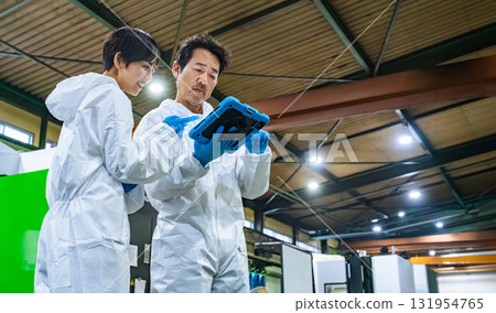 Male and female workers in protective clothing inspecting a factory 131954765