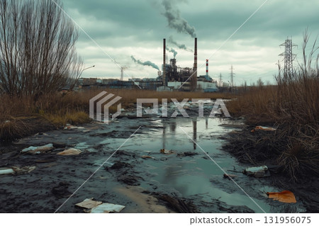 Polluted riverbed with garbage and industrial runoff flowing near the plant emitting harmful smoke polluting the environment 131956075