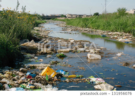River is heavily polluted with plastic garbage and industrial waste flowing through an urban area 131956076