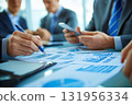Business team members are having a meeting and analyzing financial data using printed graphs and charts 131956334