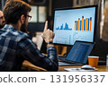 Business analyst is pointing at data on a computer screen while giving a presentation to colleagues 131956337
