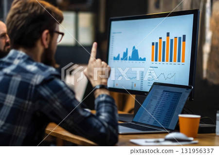 Business analyst is pointing at data on a computer screen while giving a presentation to colleagues 131956337