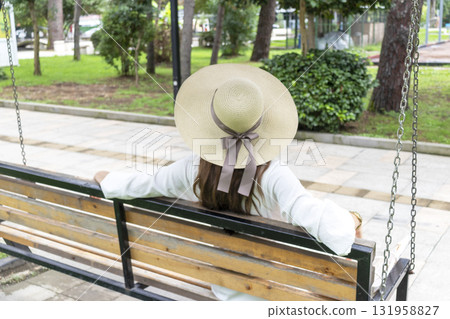Attractive woman wearing creamy, off white outfit, straw hat in the park for a walk 131958827