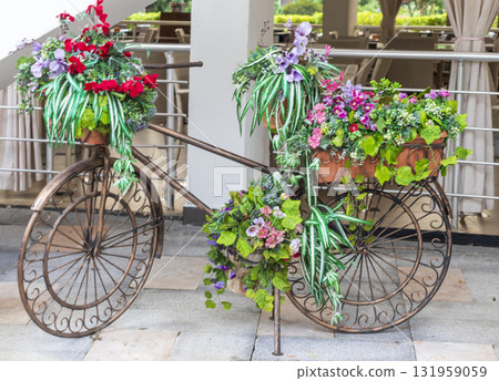 Metal decoration at the front of summer cafe, made in shape of bicycle and decorated with flowers 131959059