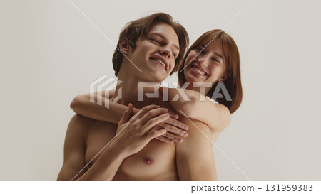 Joyful woman embracing smiling man from behind with healthy glowing skin Joyful woman embracing smiling man from behind with healthy glowing skin 131959383