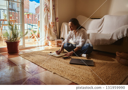 Woman Working At Home On Laptop, Writing Notes On Rug Near Balcony Woman Working At Home On Laptop, Writing Notes On Rug Near Balcony 131959990