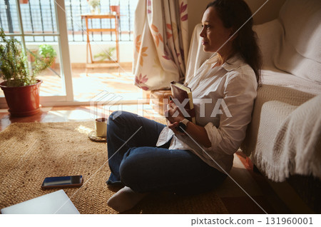 Relaxed Woman Reading Book At Home With Coffee Mug And Phone 131960001