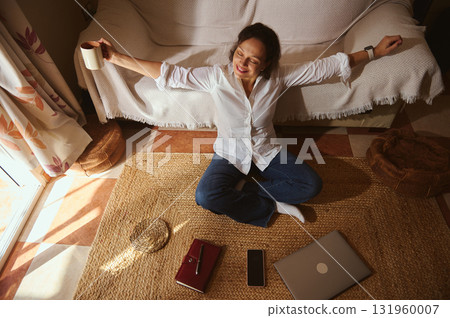 Relaxed Woman At Home Meditating With Coffee, Laptop, And Phone In Cozy Living Space Relaxed Woman At Home Meditating With Coffee, Laptop, And Phone In Cozy Living Space 131960007