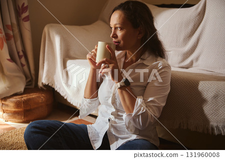 Casual Woman Sips Coffee At Home In White Shirt And Jeans Casual Woman Sips Coffee At Home In White Shirt And Jeans 131960008
