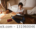 Woman Working From Home With Laptop And Phone In Cozy Living Room Setting 131960046