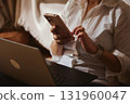 Cozy Home Office Scene With Person Using Smartphone And Laptop On Lap 131960047