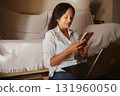 Woman Working From Home With Laptop And Smartphone, Smiling While Texting 131960050