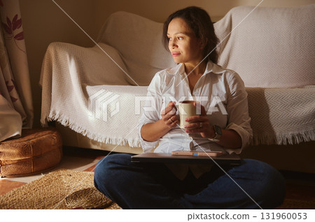 Relaxed Woman With Coffee Mug Working On Laptop In Cozy Living Room Relaxed Woman With Coffee Mug Working On Laptop In Cozy Living Room 131960053