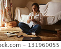 Woman Relaxing At Home With Cup Of Coffee Surrounded By Laptop And Notebook 131960055