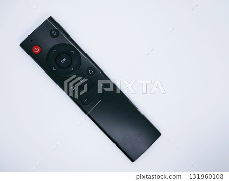 A black remote control with various buttons on a white background A black remote control with various buttons on a white background 131960108