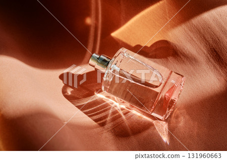 A pink perfume bottle on a soft reddish background. 131960663