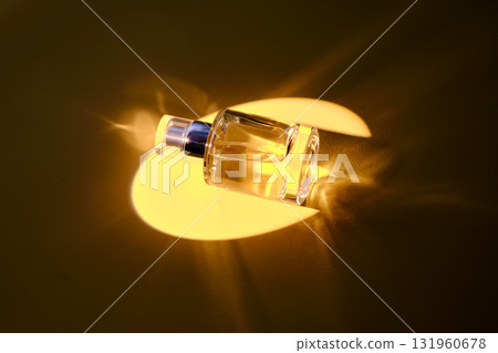 A bottle of perfume in the yellow spotlight. Golden shades. A bottle of perfume in the yellow spotlight. Golden shades. 131960678
