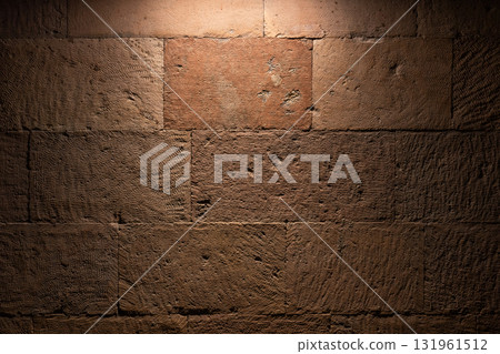 A close-up view of a rough brown stone wall illuminated from above A close-up view of a rough brown stone wall illuminated from above 131961512