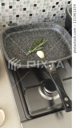 Rosemary and sage sprigs, garlic in frying pan. Spices and cooking at home in kitchen. 131961834