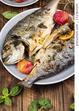 Baked dorado fish with plums served on a plate. 131962004