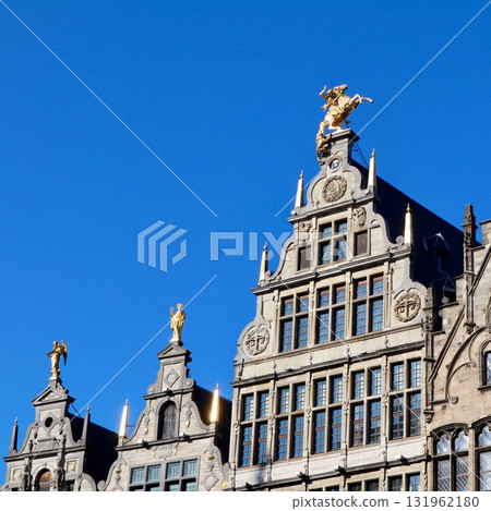 Guildhouses with golden statues against a blue sky, reflecting rich history in Grote Markt, Antwerp, Belgium 131962180