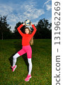 Young Woman Balancing Soccer Ball Outdoors in Bright Sports Attire and Smiling 131962269