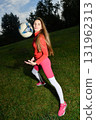 Young woman in vibrant sportswear playing with soccer ball outdoors 131962313