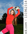 Young Woman in Vibrant Attire Posing Playfully with Soccer Ball Outdoors 131962314