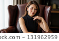 一位身穿黑色連身裙的 40 多歲女性坐在椅子上陷入沉思 131962959