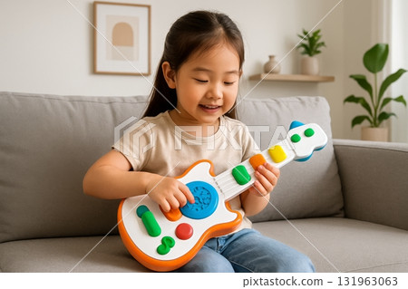 Child Plays With Colorful Toy Guitar in a Cozy Living Room During Daylight Hours 131963063