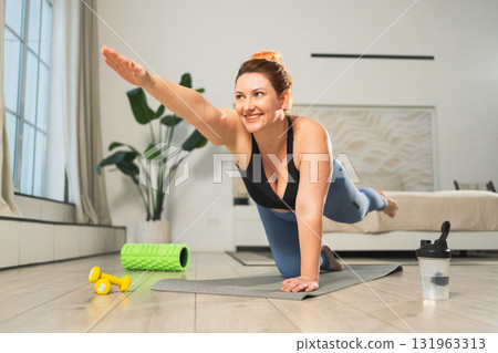 Yoga fitness workout training. Woman practicing yoga at home. Plus size female doing sports exercise on yoga mat indoor. Girl in sportswear have training workout for weight loss. Sport and fitness Yoga fitness workout training. Woman practicing yoga at home. Plus size female doing sports exercise on yoga mat indoor. Girl in sportswear have training workout for weight loss. Sport and fitness 131963313
