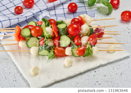 Italian appetizer with cherry tomatoes, cucumbers and mozzarella on a white board, top view Italian appetizer with cherry tomatoes, cucumbers and mozzarella on a white board, top view 131963646