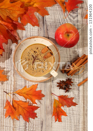 Indian masala chai with milk, ginger, anise, and cinnamon on an old wooden table with fallen autumn leaves. A traditional seasonal drink with spices, a cafe advertising card, a restaurant menu. Indian masala chai with milk, ginger, anise, and cinnamon on an old wooden table with fallen autumn leaves. A traditional seasonal drink with spices, a cafe advertising card, a restaurant menu. 131964100