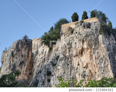 A scenic view of a majestic Rocky Cliff with an ancient fort surrounded by vibrant trees A scenic view of a majestic Rocky Cliff with an ancient fort surrounded by vibrant trees 131964161