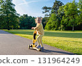 Scooter and kid. Toddler outdoor riding. Fun yellow play childhood freedom. 131964249