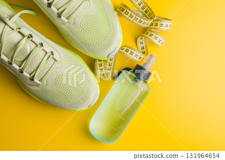 Sport running shoes and water bottle on yellow background. Top view. 131964654