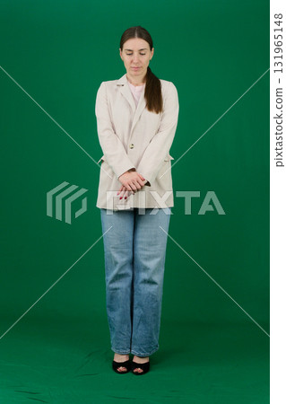 Set of photos of young European woman in light blazer and blue jeans showing various emotions gestures and expressions on green chroma key background with copy space for advertising and social media 131965148