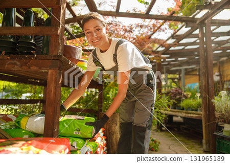 A Garden Center Employee organizes supplies in a greenhouse, showing passion for plants 131965189