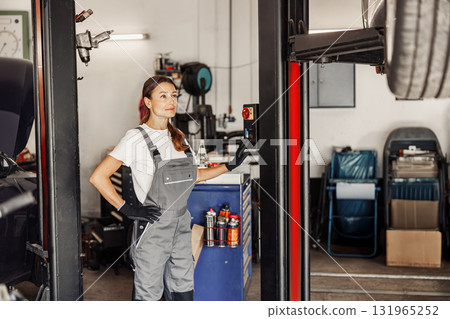 A Confident Female Mechanic working in a busy Auto Shop showcasing her skills and expertise A Confident Female Mechanic working in a busy Auto Shop showcasing her skills and expertise 131965252