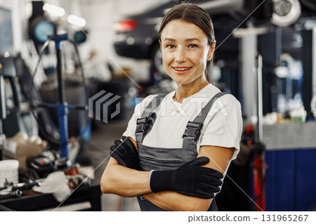 A confident female mechanic in an automotive shop, showcasing her skill and dedication A confident female mechanic in an automotive shop, showcasing her skill and dedication 131965267