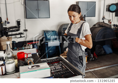 A female mechanic works in a modern garage, utilizing advanced tools and equipment 131965285