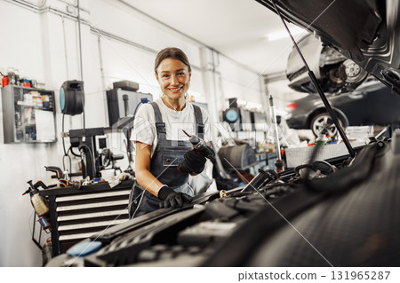 A female mechanic is diligently repairing a car in a wellequipped garage with skill A female mechanic is diligently repairing a car in a wellequipped garage with skill 131965287