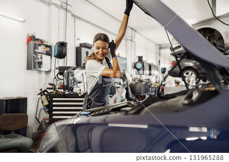 A Highly Skilled Mechanic Diligently Working on a Car Inside a Modern Garage Environment A Highly Skilled Mechanic Diligently Working on a Car Inside a Modern Garage Environment 131965288