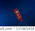 A breathtaking Aerial View capturing a Solitary Red Boat floating gracefully on Deep Blue Water 131965458