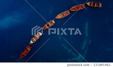 Aerial View of Rowboats Beautifully Arranged in a Serpentine Pattern Over Calm Waters 131965462