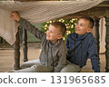 Boys hide under the Christmas table from their parents, waiting for Christmas to come. 131965685