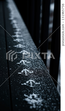 A detailed close-up perspective captures a delicate trail of small bird footprints pressed into fresh white snow covering a dark wooden surface on a cold winter morning. A detailed close-up perspective captures a delicate trail of small bird footprints pressed into fresh white snow covering a dark wooden surface on a cold winter morning. 131965756